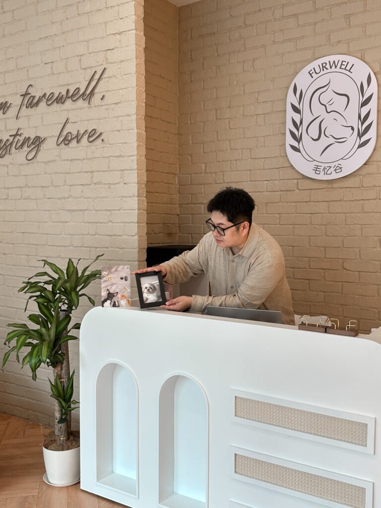 Furwell staff member at the reception desk holding a pet memorial photo frame